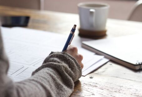 Mentorship Story - person writing on brown wooden table near white ceramic mug