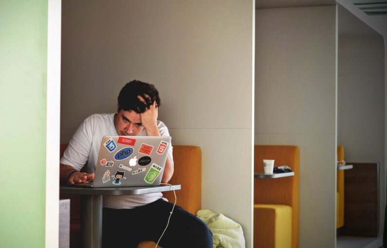 Student Debt - man wearing white top using MacBook