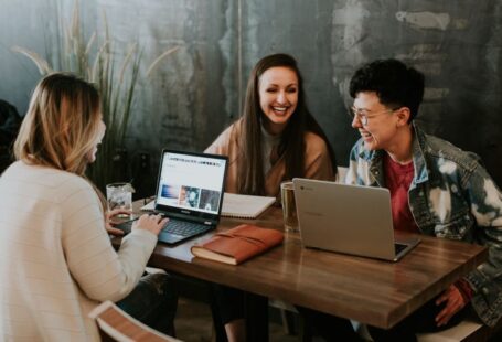 Entrepreneurial Education - three people sitting in front of table laughing together