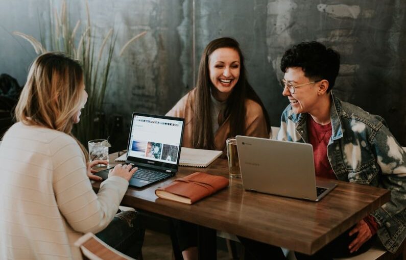 Entrepreneurial Education - three people sitting in front of table laughing together