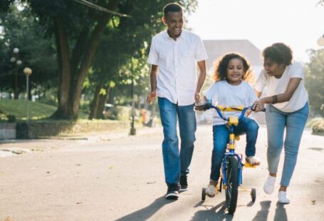 Peer Teaching - Man Standing Beside His Wife Teaching Their Child How to Ride Bicycle
