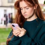 Digital Divide - Redhead Woman Standing under Tree Using Phone