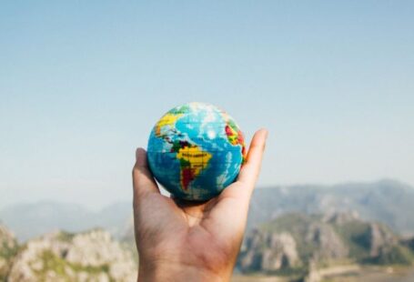 International Students - Person Holding World Globe Facing Mountain