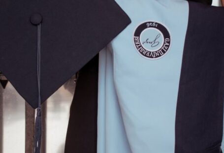Refugee Education - A woman in a graduation gown holding a diploma
