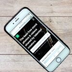 Global Network - Top view contemporary mobile phone with opened website on screen placed on wooden table