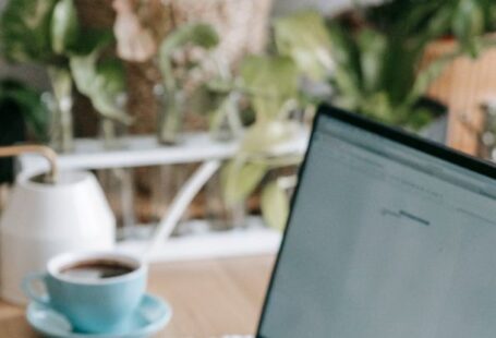 Green Jobs - Crop anonymous freelancer browsing modern netbook while sitting at table in light room with many green potted plants at home
