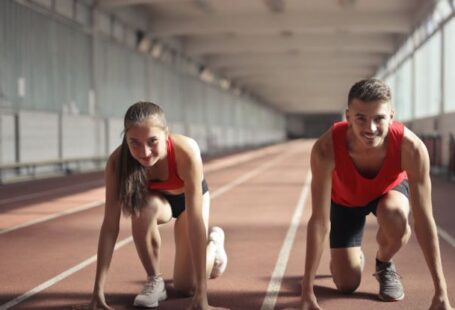 Entrepreneurial Skills - Men and Woman in Red Tank Top is Ready to Run on Track Field