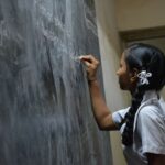 Rural Education - woman standing writing on black chalkboard