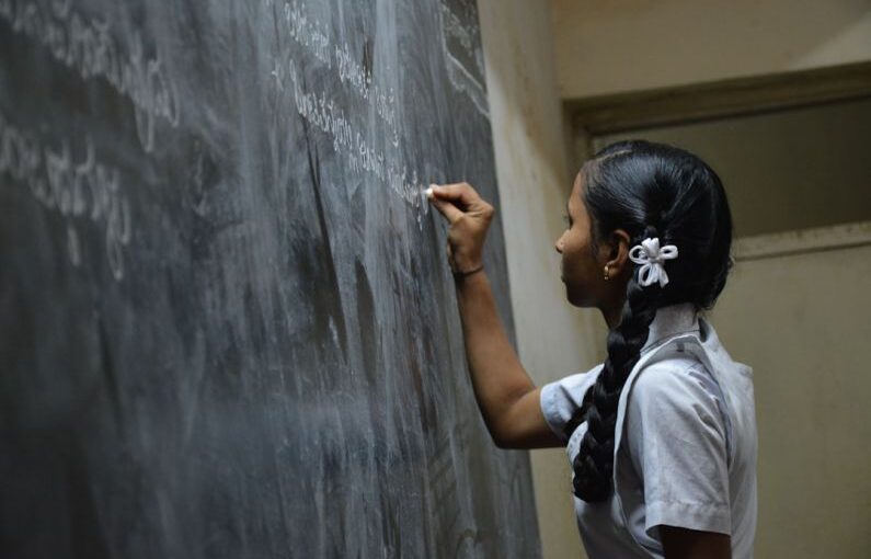 Rural Education - woman standing writing on black chalkboard