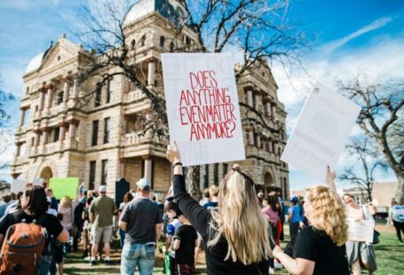 Student Activism - woman holding does anything even matter anymore? signage near building at daytime